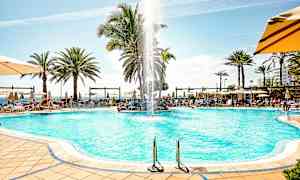 Poolområde med liggestole, parasoller og palmer. (AI-genereret tekst)