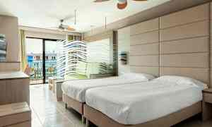 Et hotelværelse med to enkeltsenge, en siddegruppe og en altan med udsigt. (AI-genereret tekst)