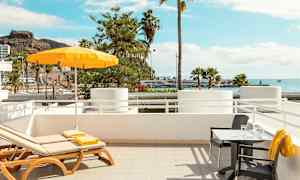 Liggestole og bord med udsigt over havet og palmer. (AI-genereret tekst)