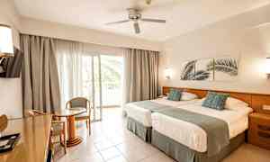 Hotelværelse med to senge, siddeområde og balkon. (AI-genereret tekst)