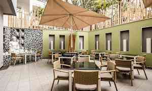 Gårdhave med borde og stole samt en stor parasol. (AI-genereret tekst)