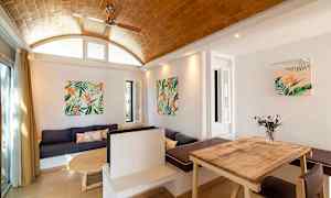 En indretning med træbord, sofa og vægdekorationer med plantemotiver. (AI-genereret tekst)