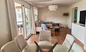 Moderne indrettet stue- og køkkenområde med glasbord, sofa og lænestol. (AI-genereret tekst)