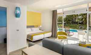 Et hotelværelse med farverigt interiør og udsigt til en have med pool. (AI-genereret tekst)