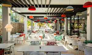 En moderne restaurant med mange farverige stole og borde. (AI-genereret tekst)