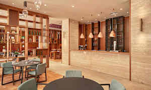 Interiør af en restaurant med moderne indretning, inklusive borde, stole og en bardisk. (AI-genereret tekst)