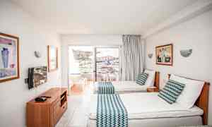 Hotelværelse med to enkeltsenge, balkon med udsigt over omgivelserne. (AI-genereret tekst)