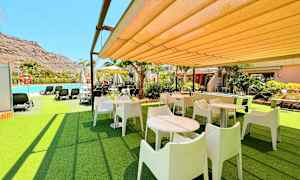 Udendørsområde med borde, stole og nærliggende pool. (AI-genereret tekst)