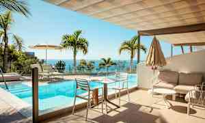 En terrasse med en pool og udsigt over havet, omgivet af palmer. (AI-genereret tekst)