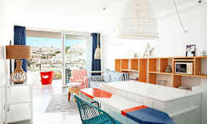 Lyst indrettet lejlighed med farverige møbler og udsigt til et bjerg gennem altandøren. (AI-genereret tekst)