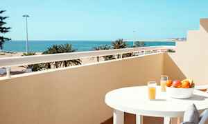 Altan med havudsigt, et bord med frugtskål og glas med juice. (AI-genereret tekst)