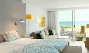 Hotelværelse med udsigt over en sandstrand og havet. (AI-genereret tekst)