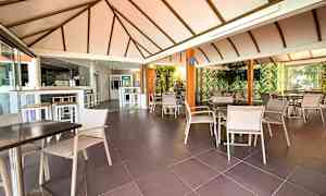 Restaurant med siddegrupper og loft med bjælker. (AI-genereret tekst)