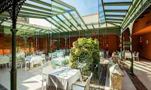 Indendørs servering med glasvægge og -tag, dekoreret med grønne planter og borde. (AI-genereret tekst)