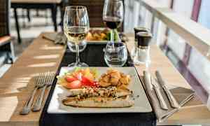 En tallerken med fisk, grøntsager og kartofler samt et glas hvidvin. (AI-genereret tekst)