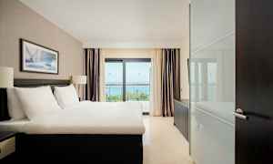 Hotelværelse med en dobbeltseng, vindue med havudsigt. (AI-genereret tekst)