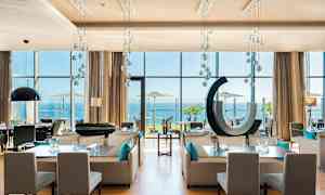 Moderne restaurant med store vinduer mod havet. (AI-genereret tekst)