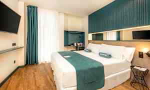 Et moderne hotelværelse med en dobbeltseng, vægmonteret TV og minimalistisk indretning. (AI-genereret tekst)