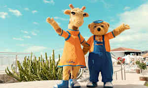 To figurer i dyrekostumer, en giraf og en bjørn, står side om side og hilser, iført farverige tøj. (AI-genereret tekst)