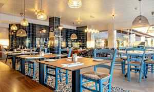 En restaurant med borde og blå stole. (AI-genereret tekst)