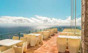 Terrasse med borde og stole ved havet. (AI-genereret tekst)