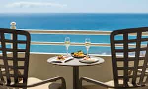 To tallerkener med mad og to glas med drikke på et bord med havudsigt. (AI-genereret tekst)