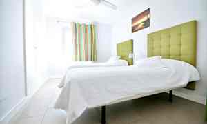 Et værelse med to enkeltsenge med grøn polstret sengegavl. (AI-genereret tekst)