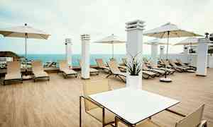 En terrasse med liggestole, parasoller og udsigt over havet. (AI-genereret tekst)