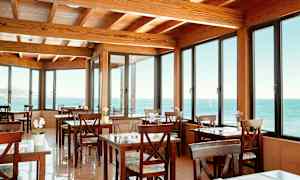 En café med træborde og stole, med store vinduer der viser havudsigt. (AI-genereret tekst)