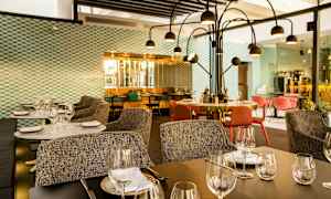 Moderne restaurant med dækkede borde, stole og dekorativ belysning. (AI-genereret tekst)