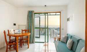 Et rum med spisebord og stole, sofa og glasdør til en altan. (AI-genereret tekst)