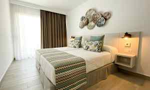 Et soveværelse med en dobbeltseng, pyntepuder og et dekoreret hovedgærde. (AI-genereret tekst)