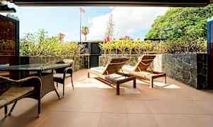 En terrasse med liggestole, bord og stole samt omgivet af planter. (AI-genereret tekst)