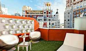 Tagterrasse med siddemøbler og udsigt over byens arkitektur. (AI-genereret tekst)