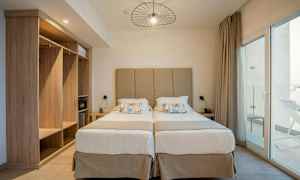 To enkeltsenge med beige sengegavl og natborde på hver side. (AI-genereret tekst)