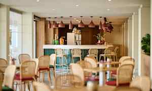 En lys og moderne indendørsbar med bardiske og borde placeret rundt omkring. (AI-genereret tekst)