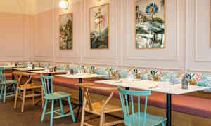 En restaurant med borde og stole, billeder på væggen og bløde sofaer langs væggen. (AI-genereret tekst)