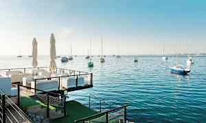 Udeservering ved havet med sejlbåde på vandet. (AI-genereret tekst)