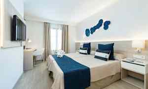 Hotelværelse med to senge og maritimt tema, blåt sengetøj og dekorative puder. (AI-genereret tekst)