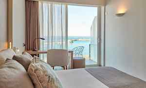 Et hotelværelse med udsigt til havet gennem vinduet. (AI-genereret tekst)