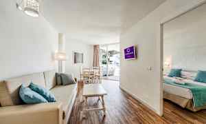 Billede af et hotelværelse med stue, sofa, spisebord og tilstødende soveværelse. (AI-genereret tekst)