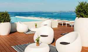 Loungeområde ved en pool med moderne møbler og udsigt over havet. (AI-genereret tekst)