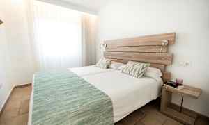 To enkeltsenge med grønne sengetæpper i et lyst rum. (AI-genereret tekst)