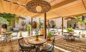 Indergård med havemøbler og planter under en skærmtag. (AI-genereret tekst)