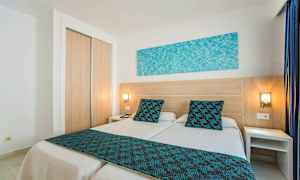 Et hotelværelse med to enkeltsenge med blå detaljer. (AI-genereret tekst)