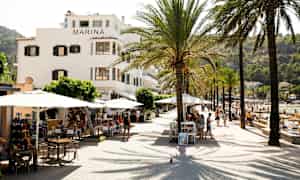 En gade med palmer, borde og bygningen Marina ved siden af en strand. (AI-genereret tekst)