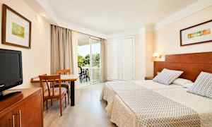 Billede af et hotelværelse med to enkeltsenge, et skrivebord med stole og en altan. (AI-genereret tekst)