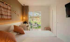 Et hotelværelse med to senge, dekorativ vægdekoration og en terrasse med udsigt til grønt område. (AI-genereret tekst)