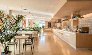 Lyst og moderne spiseområde med borde, stole og buffetanretning. (AI-genereret tekst)