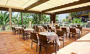 Udeservering med opdækkede borde, stole og haveomgivelse i baggrunden. (AI-genereret tekst)